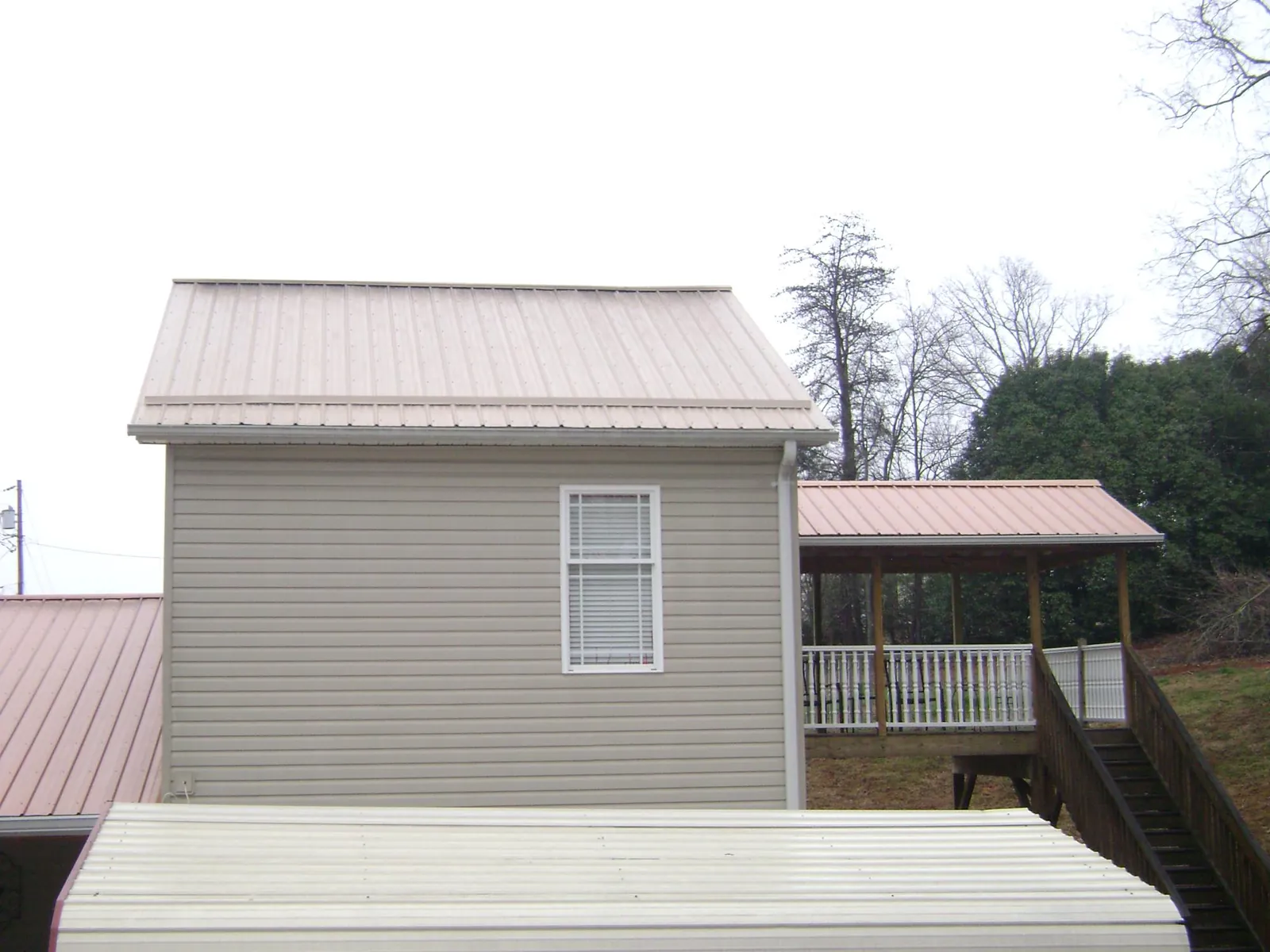Tan metal roofs on a two story addition and attached porch, from a Roof Replacement job in Sylvania